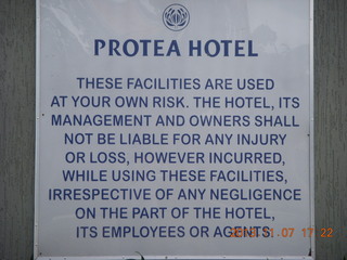 113 8f7. Uganda - Entebbe - Protea Hotel - sign (too many lawyers)